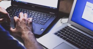 a hand of a person operating two laptops indicating how cloud servers are keeping the internet running during the pandemic