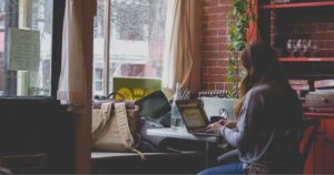 a woman inside a cafe operating a laptop indicating internet traffic is up and that's okay